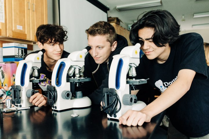 HS boys science classroom microscope